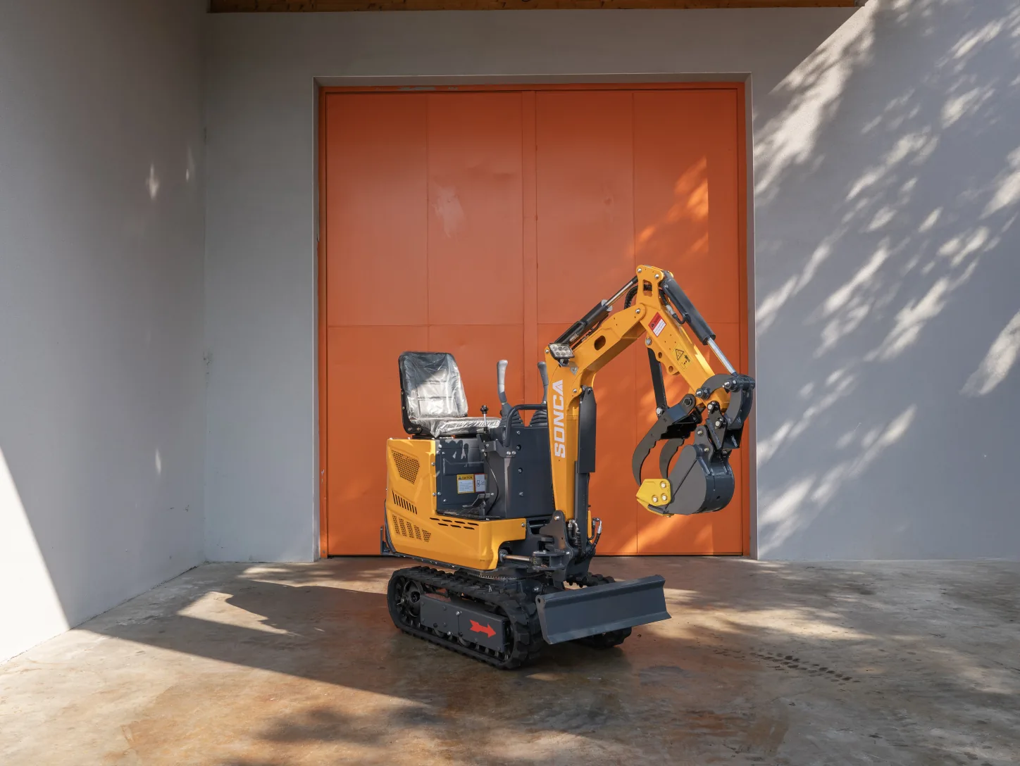 Mini-pelle Sonca SJW-06 de 660 kg — vue trois quarts avant, godet et lame de remblayage