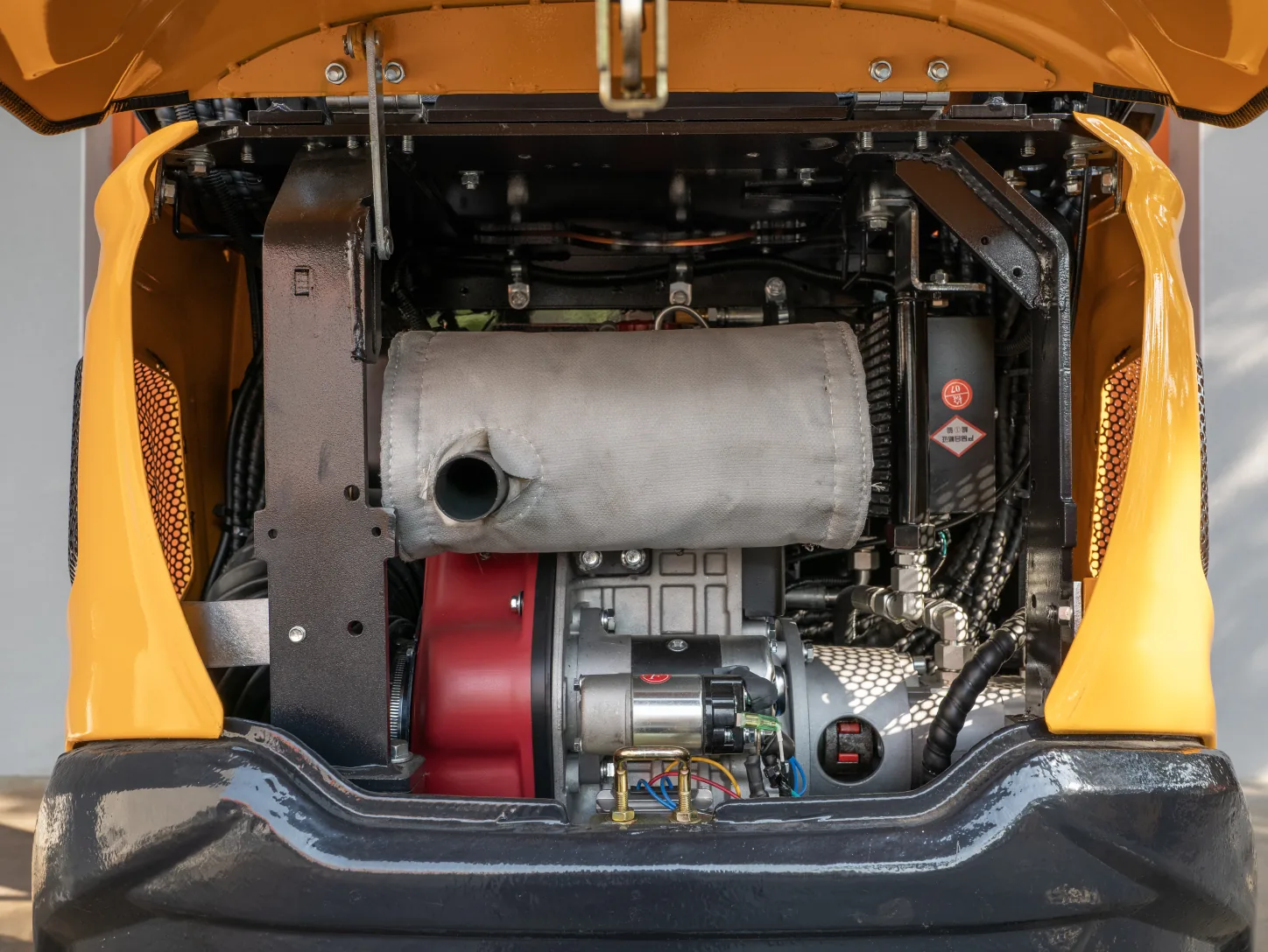 Compartiment moteur ouvert de la mini-pelle Sonca SJW-12 P : moteur diesel, silencieux gainé et démarreur électrique