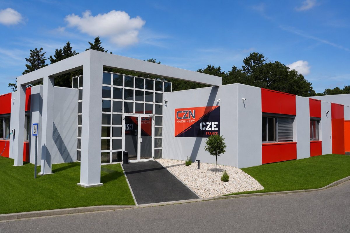 Facade of the CZN Machinery offices near Toulouse: a modern grey and red building with the CZN Machinery sign, a glass entrance and an EV charging point — headquarters of the direct importer of mini excavators and construction machines